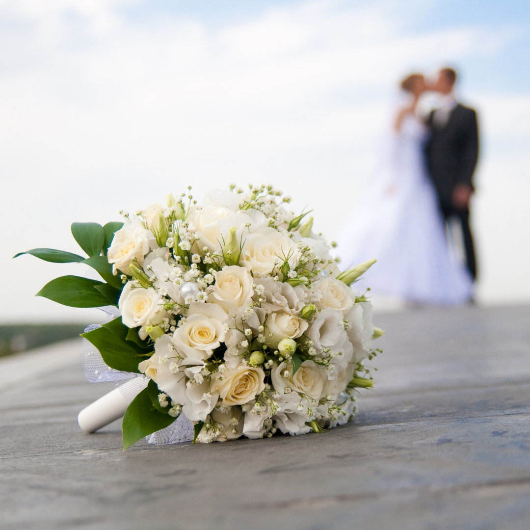 Flowers laying on a rock next to a married couple.